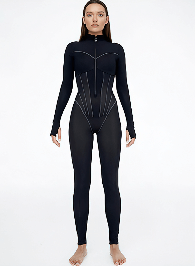 Woman wearing black sports jumpsuit with long sleeves and front zipper, sleek fit for active lifestyle.